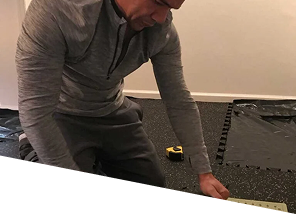 man-cutting-rubber gym-floor-tile-with-utility-knife-and-measuring-tape