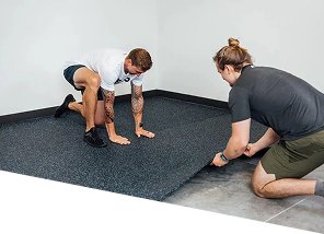 two-people-laying-black-speckled-rubber-gym-flooring-tiles